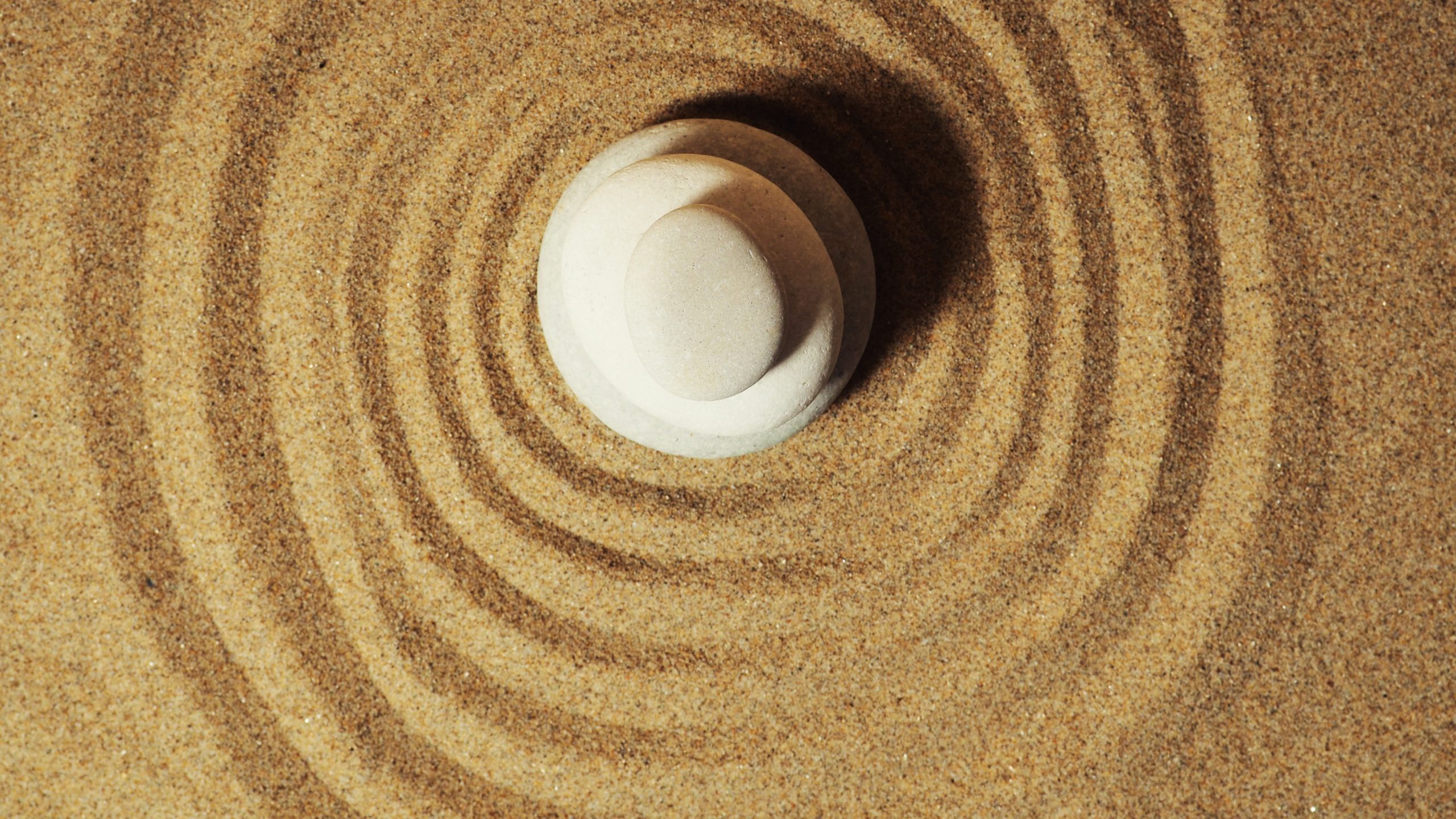 Zen garden. Pyramids of white and gray zen stones on the white sand with abstract wave drawings.