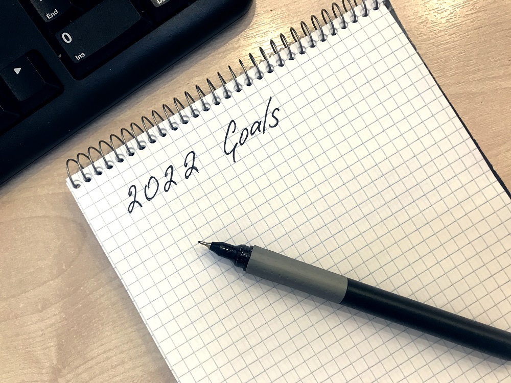 Notepad and pen on wooden table. Goals for 2022 empty list. New year resolutions and plans